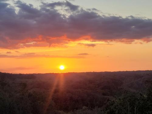 a sunset with the sun setting over a forest at Hacienda en Los Volcanes in Hacienda Guayabo