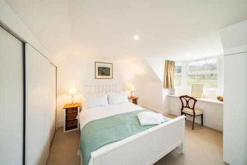 a white bedroom with a bed and a window at Westerpark Countryside Cottage in Huntly