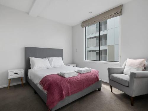 - une chambre avec un lit, une chaise et une fenêtre dans l'établissement Beautiful Sky Tower View Home near K' Road w/ Free Parking, à Auckland