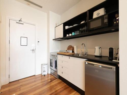 a kitchen with white cabinets and a black counter top at 1BR CBD Escape Near Sky Tower Zodiak Stays in Auckland