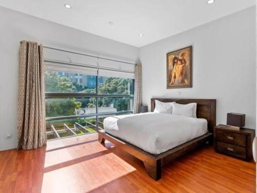 een slaapkamer met een bed en een groot raam bij Sleek Modern Pad next to Spark Arena Free Parking in Auckland