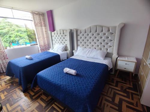 1 dormitorio con 2 camas con sábanas azules y ventana en SUMAQ PUÑUY HOSTEL - LIMA AIRPORT, en Lima