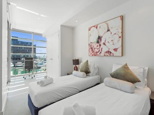 two beds in a white room with a large window at Gorgeous 2BR in Wynyard Quarter by Zodiak Stays in Auckland