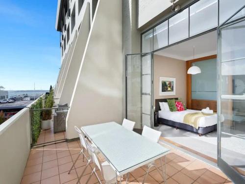 Un dormitorio con una cama y una mesa en el balcón. en Lovely Bright Apt with Pool and Gym by Zodiak Stays, en Auckland