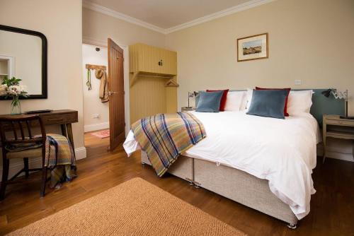 1 dormitorio con 1 cama blanca grande y escritorio en Pentland Cottage, en Norham