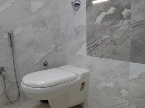 La salle de bains est pourvue d'une douche et de toilettes blanches. dans l'établissement Galaxy Vaibhav, à Vasai