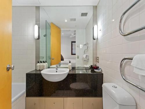 a bathroom with a sink and a toilet and a mirror at Lovely view apartment - free parking, pool and gym in Auckland