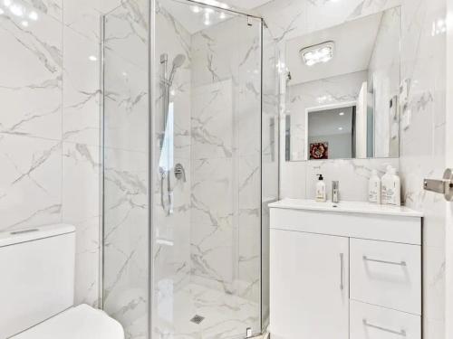 a white bathroom with a shower and a sink at Stunning Three Bedroom Townhouse with Free Parking in Auckland