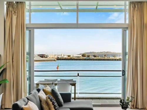 a living room with a large window looking out at the water at Relaxing Sea Wharf View Apartment by Zodiak Stays in Auckland