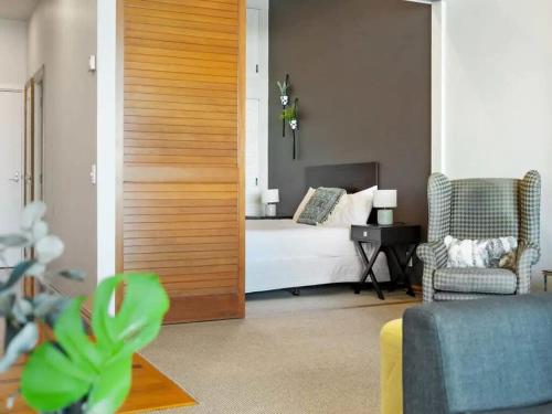 a room with a bedroom with a bed and a chair at Relaxing Sea Wharf View Apartment by Zodiak Stays in Auckland