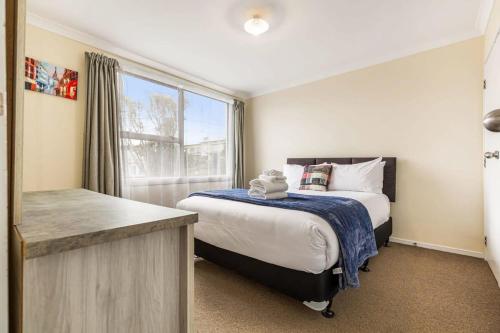 um pequeno quarto com uma cama e uma janela em Lovely 2-Bedroom Apartment with Free Parking em Auckland
