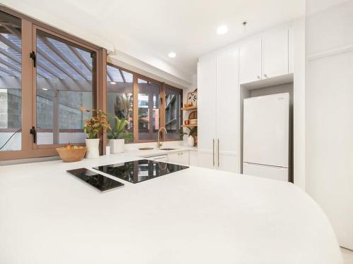 オークランドにあるCharming 1 Bedroom Apartment in Aucklandの白いキッチン(ガラスのカウンタートップ付)