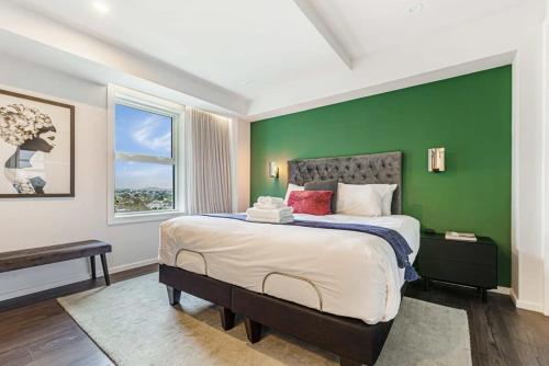 1 dormitorio con 1 cama grande y pared verde en Awesome Apartment w Parking, en Auckland