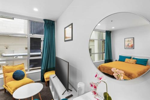 1 dormitorio con cama y espejo en Cosy and central studio, en Auckland