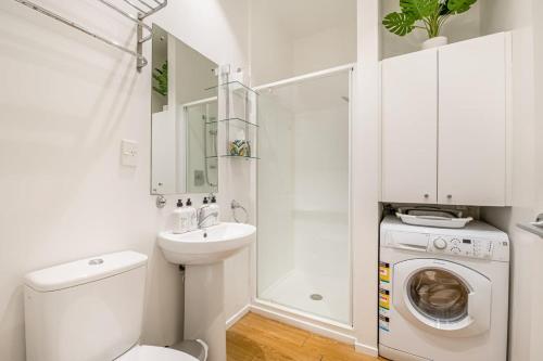 La salle de bains blanche est pourvue d'un lavabo et d'un lave-linge. dans l'établissement Open-plan living in the heart of Auckland, à Auckland