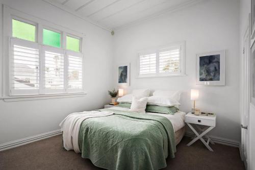 a white bedroom with a bed and two windows at Three-Bedroom Grey Lynn Villa in Auckland