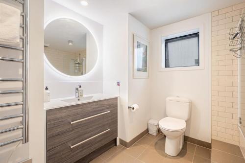 a bathroom with a toilet and a sink and a mirror at Stylish and serene living in Kohimarama in Auckland