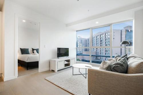 a living room with a couch and a bed and a television at Modern Bright Central Apartment by Zodiak Stays in Auckland