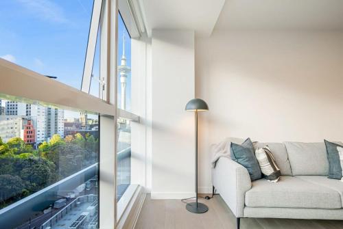 a living room with a couch and a large window at Modern Bright Central Apartment by Zodiak Stays in Auckland