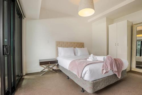 Un dormitorio con una cama con una manta rosa encima. en Bright & modern 1BR in Auckland CBD by Zodiak Stays, en Auckland