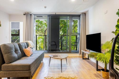 a living room with a couch and a flat screen tv at Auckland City Charm - 2BR Haven by Zodiak Stays in Auckland