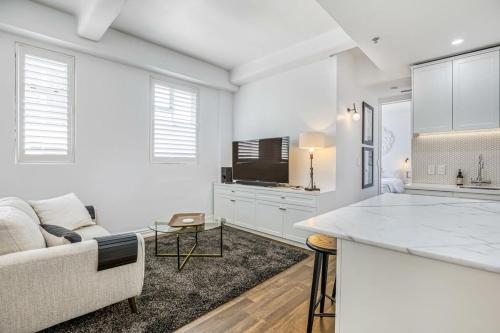 een witte woonkamer met een bank en een tv bij Stylish Central Penthouse in Auckland