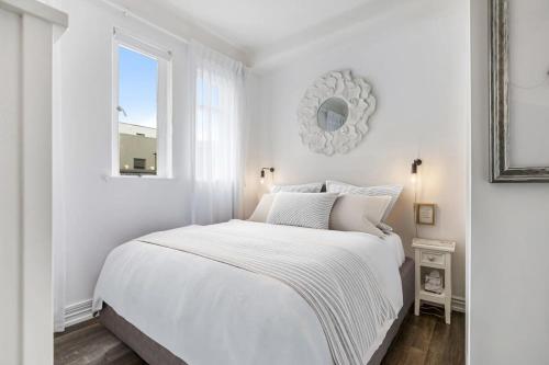 een witte slaapkamer met een wit bed en een raam bij Stylish Central Penthouse in Auckland