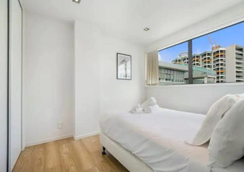 a white bedroom with a large window and a bed at Central two-bedroom apartment close to Spark Arena in Auckland