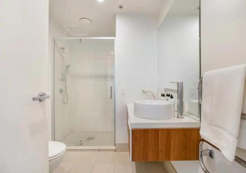 y baño blanco con lavabo y ducha. en Central two-bedroom apartment close to Spark Arena en Auckland