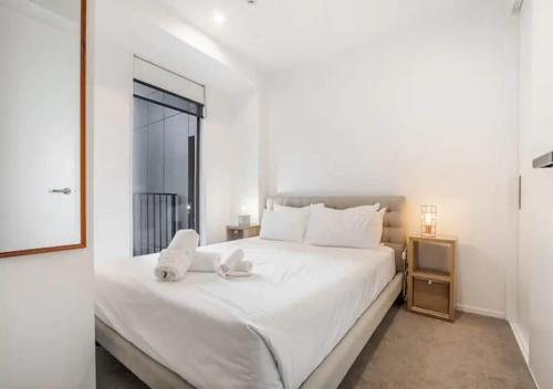 um quarto branco com uma grande cama branca e uma janela em Classy and contemporary living em Auckland