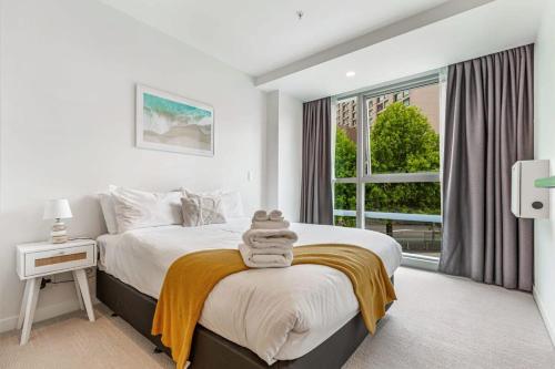 a white bedroom with a large bed and a window at At the cultural heart of Auckland CBD in Auckland