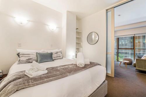 um quarto com uma grande cama branca com toalhas em Retro style on Queen Street em Auckland