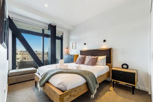 a bedroom with a large bed and a large window at Modern living in prime location in Auckland