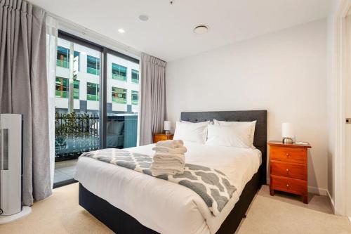 a bedroom with a bed and a large window at Spacious Mount Eden Apartment in Auckland