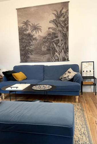 - un canapé bleu dans le salon orné d'un tableau dans l'établissement COCON ART DECO - ARCACHON CENTRE & PLAGE - L'Europe, à Arcachon