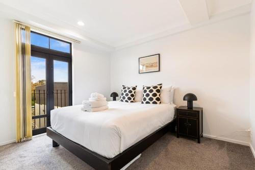 a white bedroom with a large bed and a window at Immaculate city-fringe apartment in Auckland