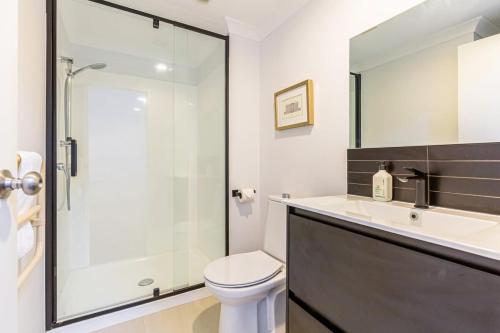 een badkamer met een douche, een toilet en een wastafel bij Immaculate city-fringe apartment in Auckland