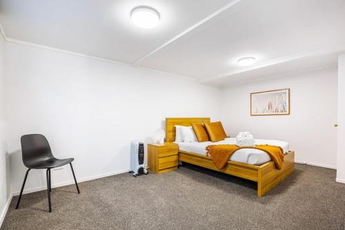 Freshly renovated Grey Lynn 3BR unit في أوكلاند: غرفة نوم فيها سرير وكرسي