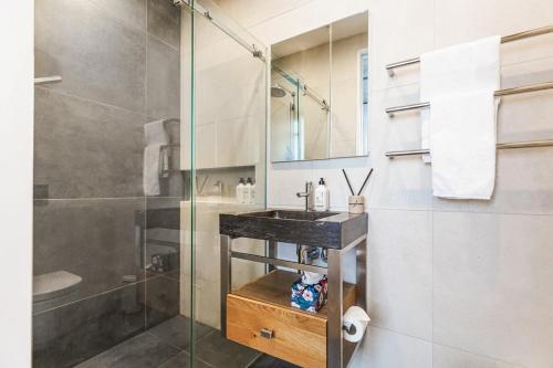 uma casa de banho com uma cabina de duche em vidro e um lavatório. em Luxury meets location - 2RB in Ponsonby em Auckland