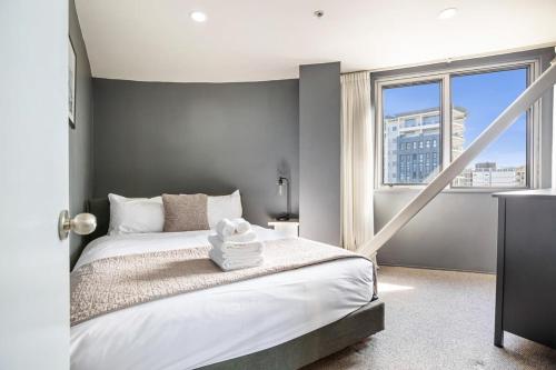 a bedroom with a bed and a large window at Downtown Auckland Bliss - 2BR apt I Zodiak Stays in Auckland