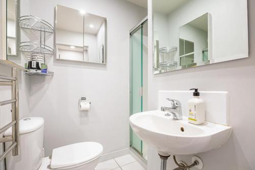 a white bathroom with a sink and a toilet at Downtown Auckland Bliss - 2BR apt I Zodiak Stays in Auckland