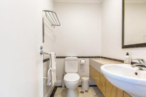 a bathroom with a white toilet and a sink at City views from 1BR Queen St apartment in Auckland