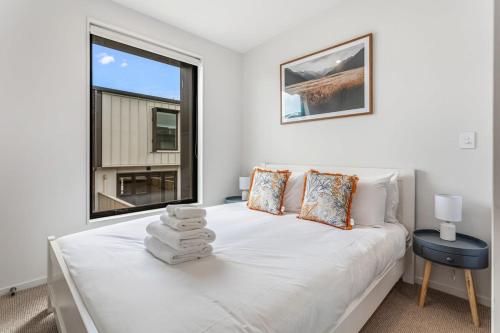 a bedroom with a white bed with a window at Fresh & sleek Grey Lynn unit with private patio in Auckland