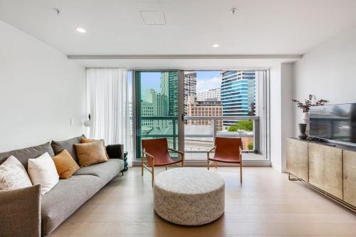 a living room with a couch and a large window at Urban Escape Prime Location by Zodiak Stays in Auckland