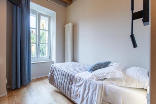 a white bedroom with a bed and a window at Albergo Del Sole in Varenna