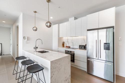 a kitchen with white cabinets and a kitchen island with stools at Urban Escape Prime Location by Zodiak Stays in Auckland