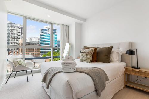 a white bedroom with a bed and a large window at Urban Escape: Prime Location in Auckland