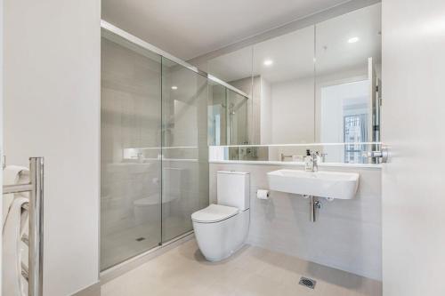 a white bathroom with a toilet and a sink at Urban Escape: Prime Location in Auckland