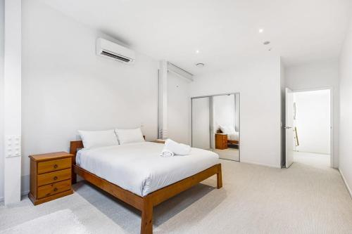 - une chambre blanche avec un lit et un miroir dans l'établissement Contemporary 1BR Queen Street Retreat, à Auckland