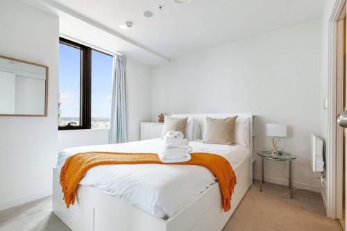 a white bedroom with a white bed with an orange blanket at Vibrant Minimalism - City Views in Auckland